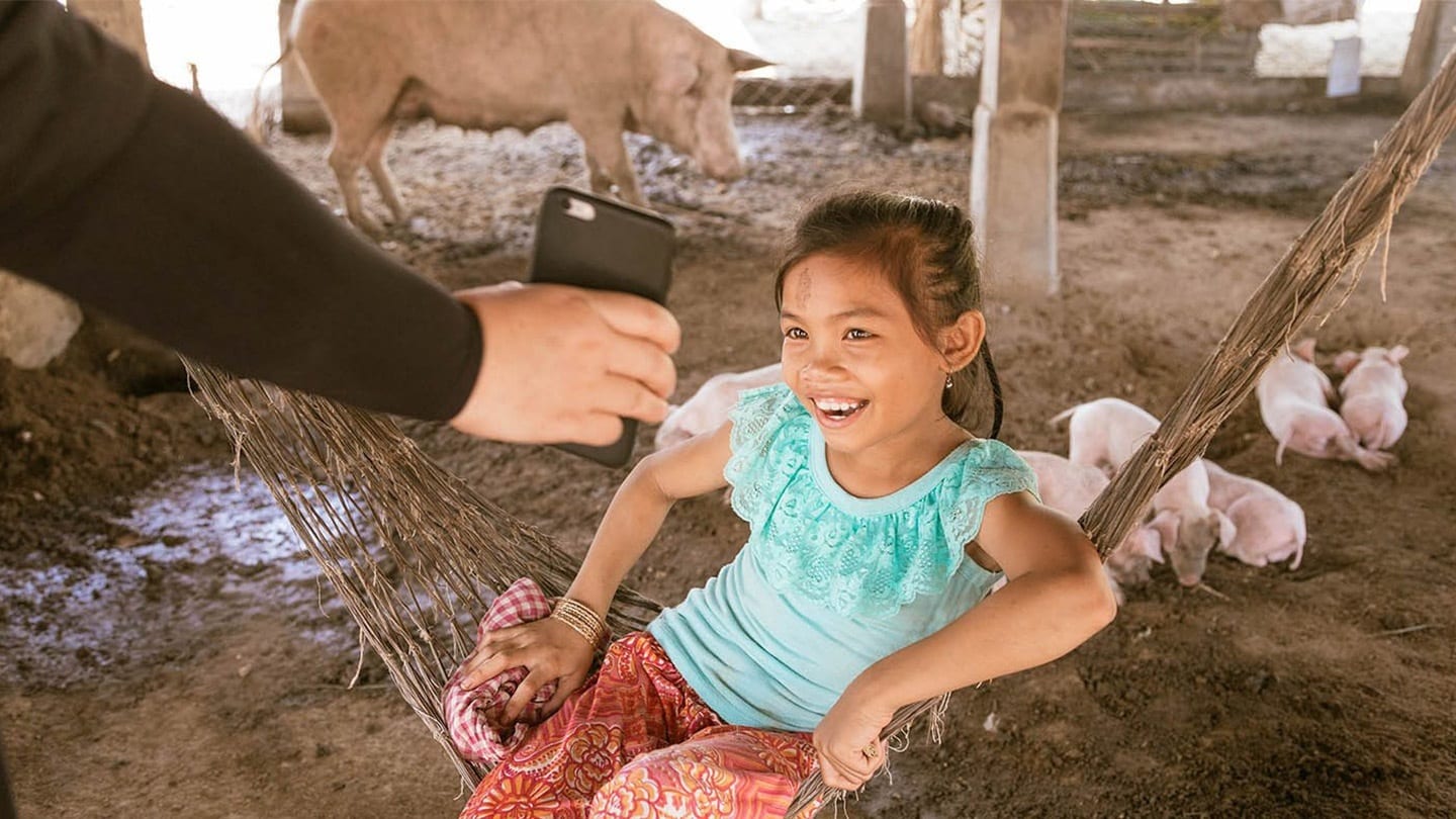 girl in blue shirt playing in a pigpen