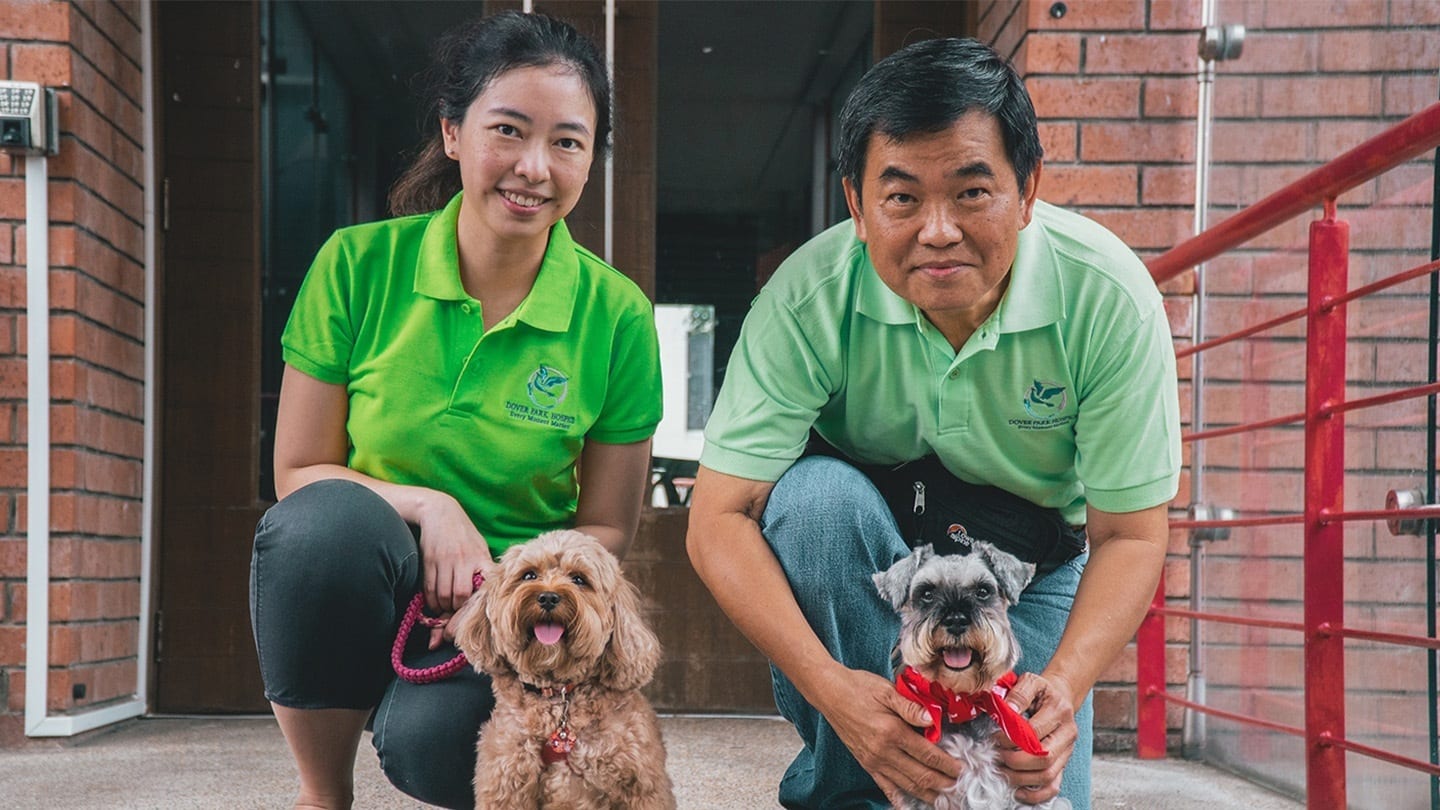 male and female volunteers in green with two dogs