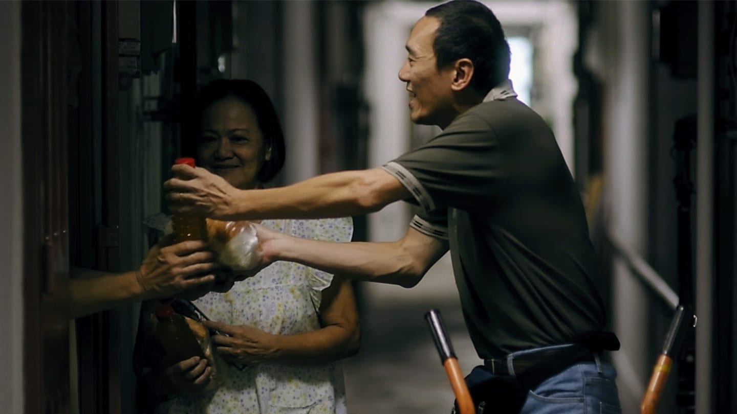 volunteers passing drinks to tenant through gate of flat