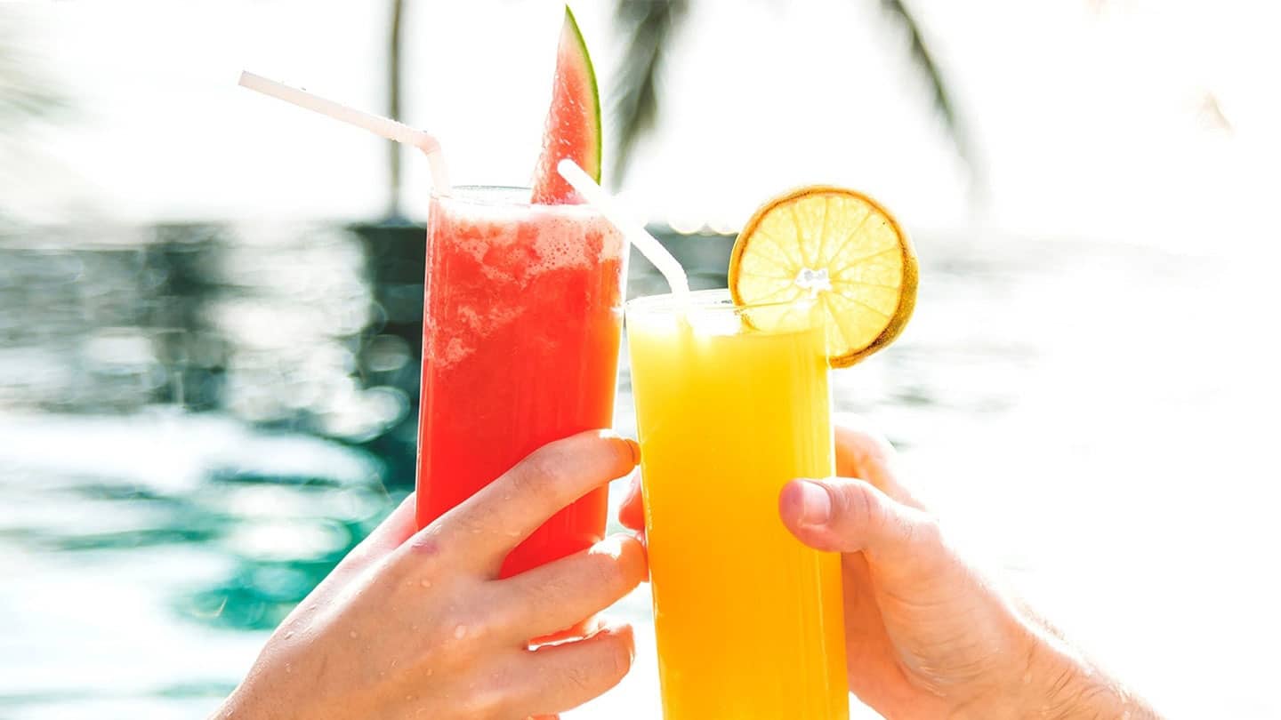 two people clinking glasses of watermelon and lemon juice together