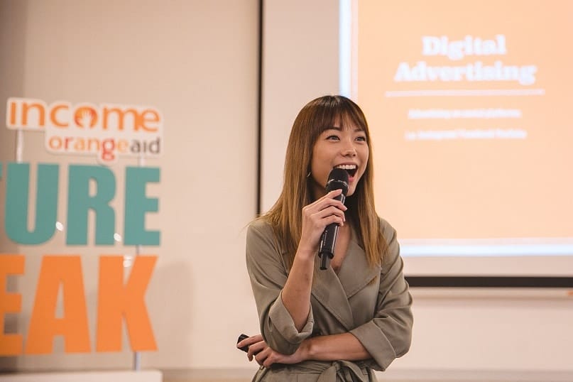 income orangeaid woman in dyed brown hair giving a presentation on digital advertising