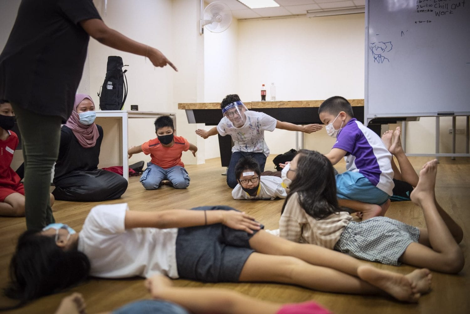 children and volunteers sitting in a circle and flopping around on the floor