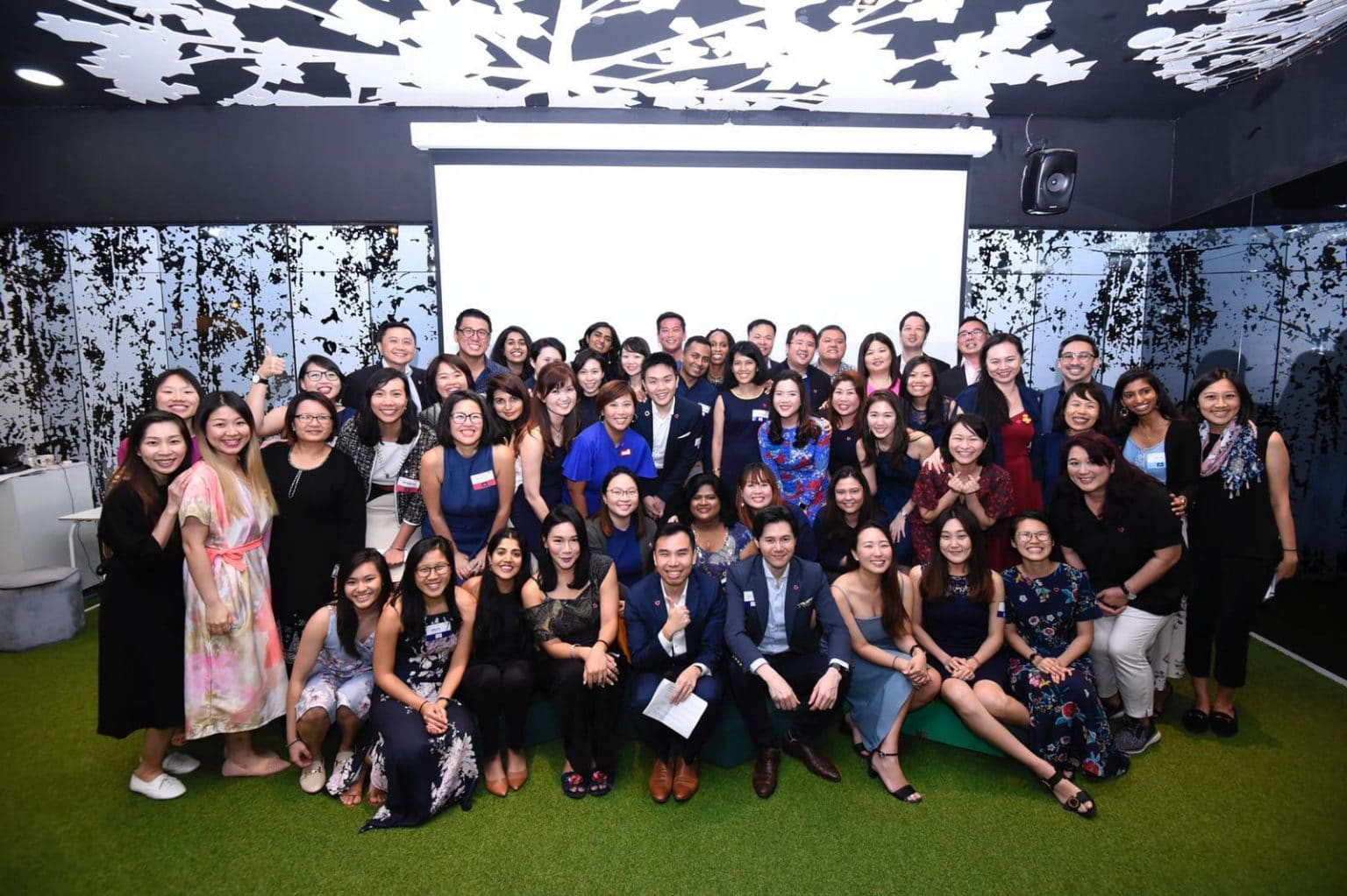 many people in formal wear gathered in front of a projector