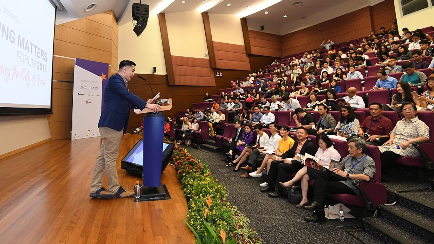 man in blue suit jacket giving a talk at a lecture theatre