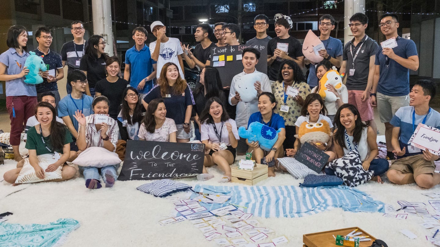 youths in blue posing for a group photo with a black sign saying welcome to the friendzone