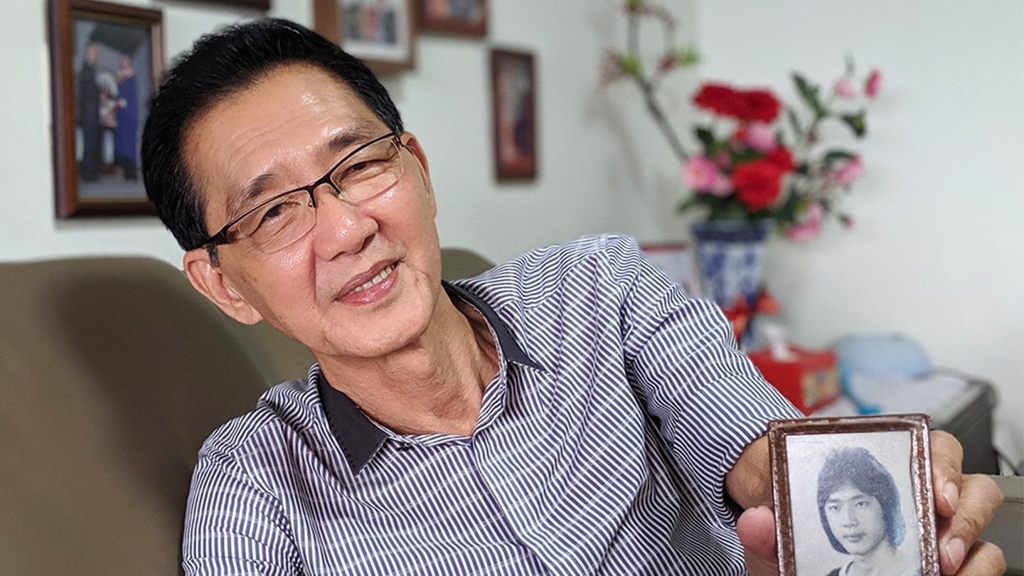 man in black and white striped shirt holding up a black and white photo of a lady