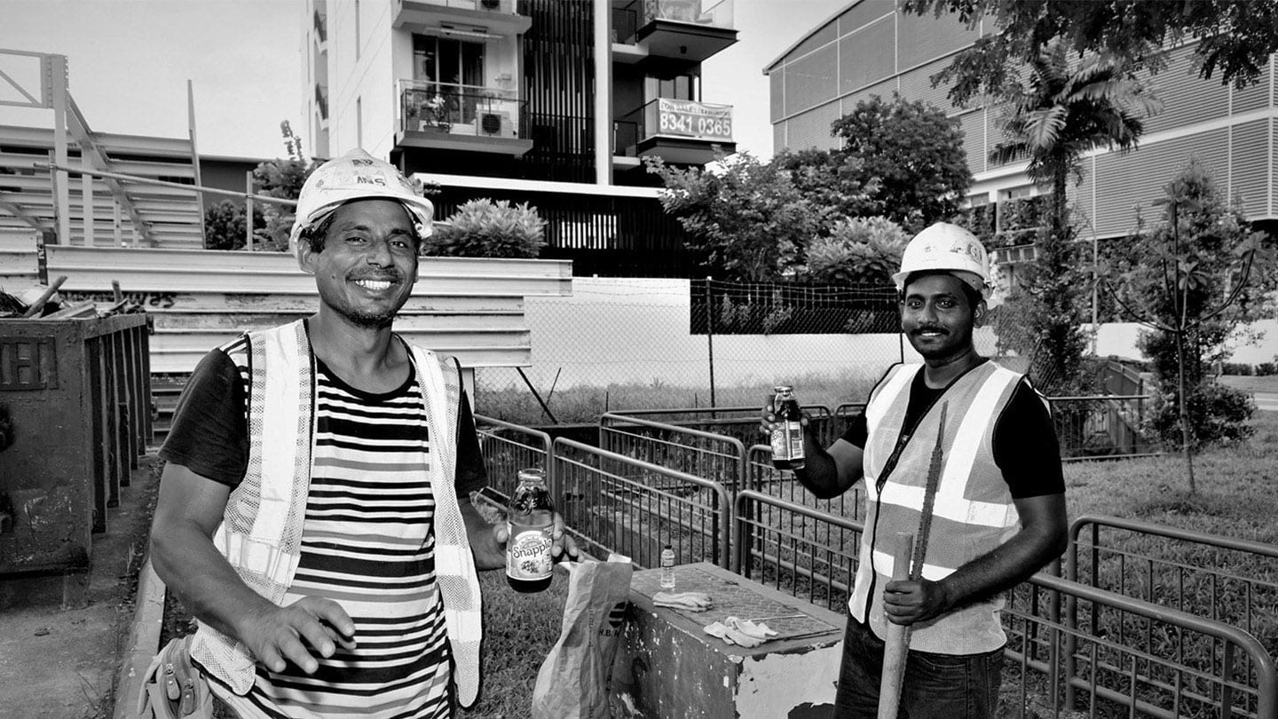 black and white photo of migrant workers in safety vests and helmets