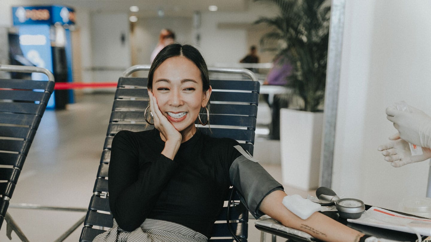 woman in hoop earrings and long-sleeved black shirt donating blood