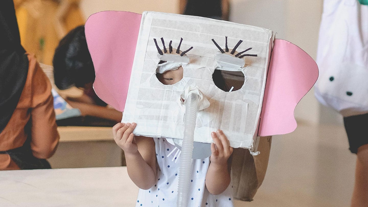 girl wearing a cupboard box decorated to look like an elephant with pink ears