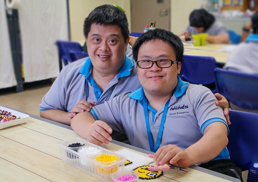 two special needs pupils at MINDS working on a smiley face bead artwork