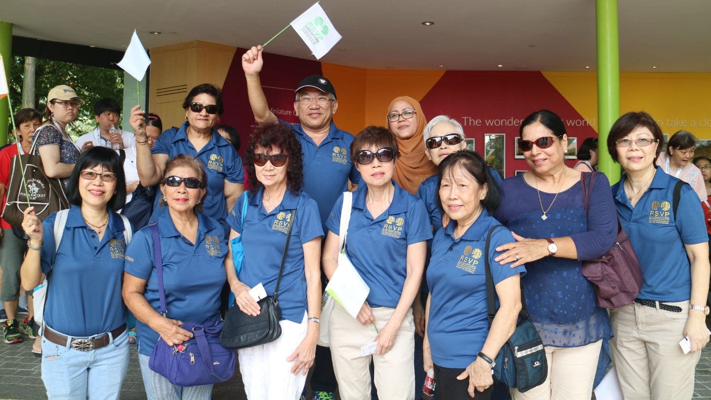 senior volunteers wearing blue rsvp shirt and waving white flags