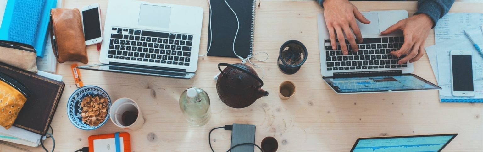 office table covered with laptops bowls of cereal kettles and cups of coffee