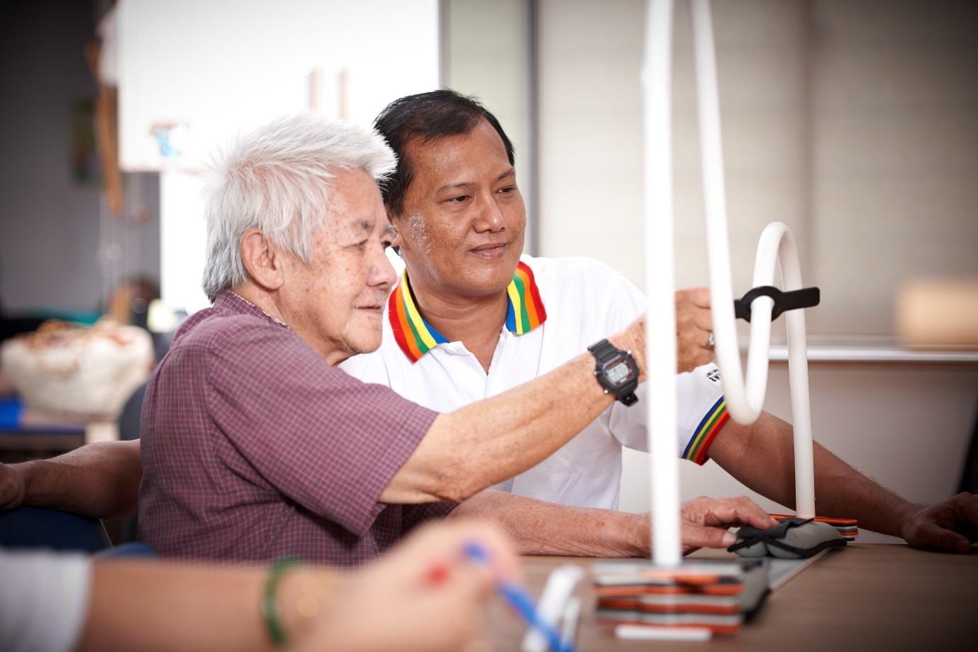 elderly man in purple shirt and man in white shirt with rainbow collar