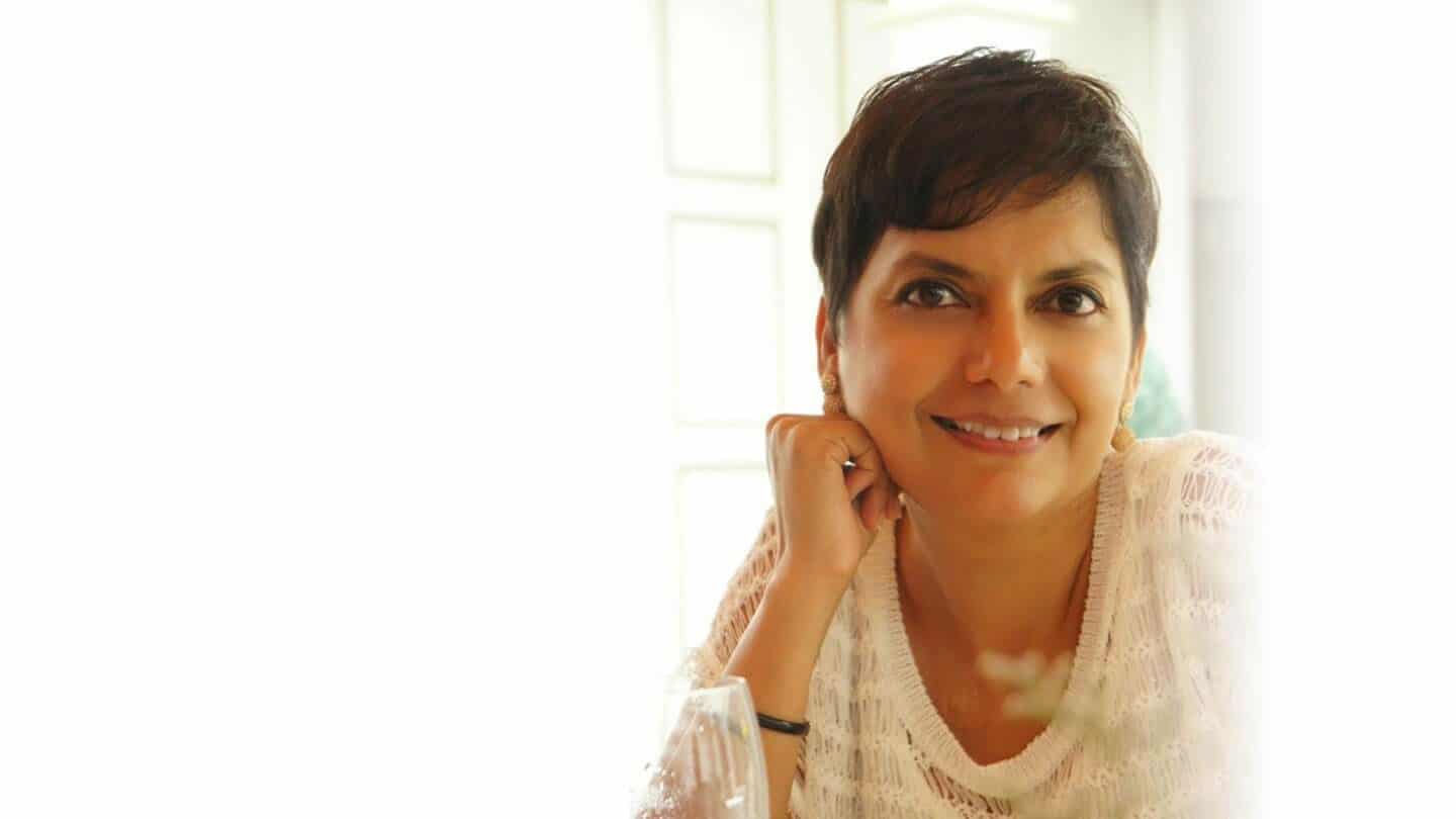 woman in pixie cut and white blouse smiling at camera