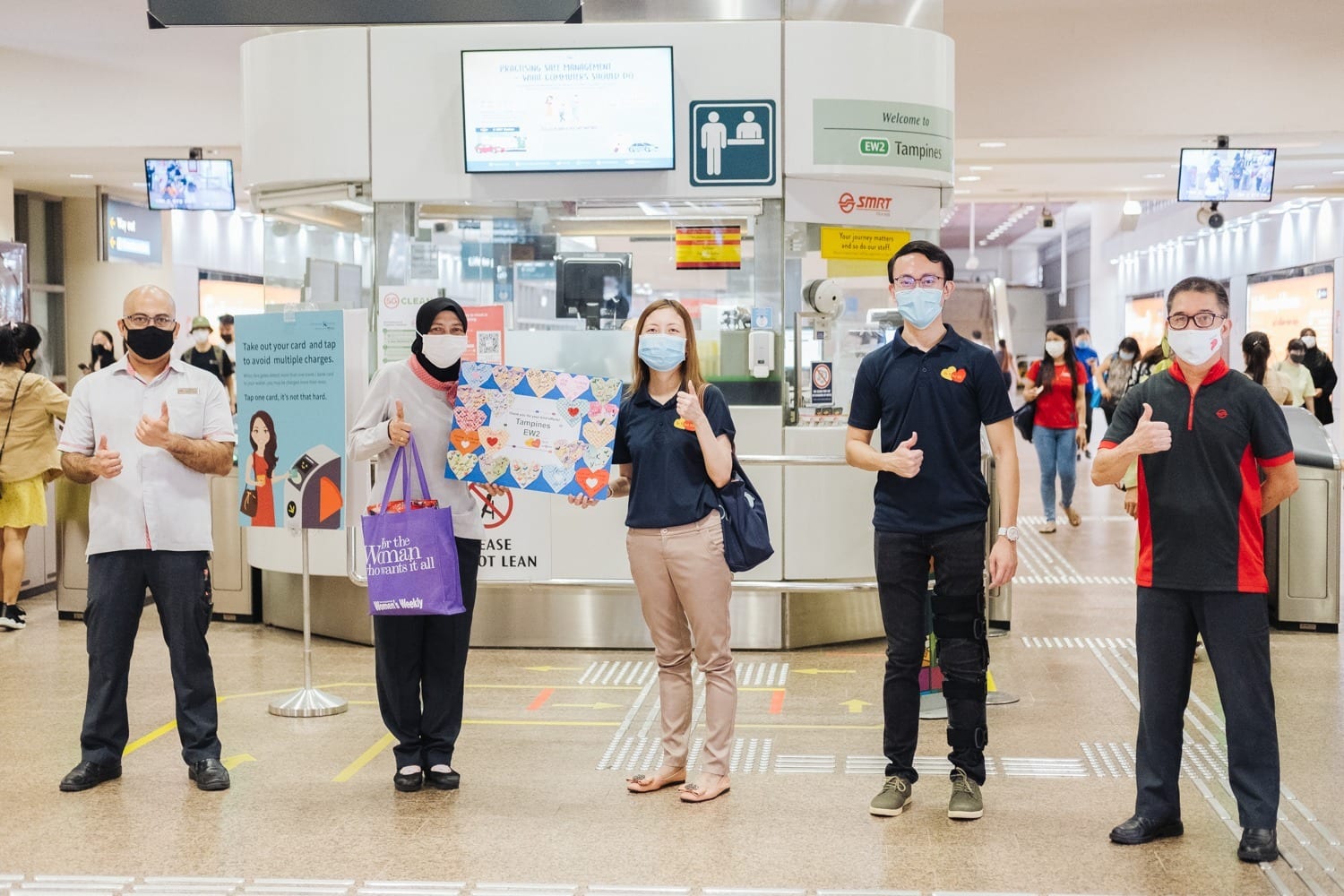 five mrt volunteers posing in front of gantry at tampines mrt