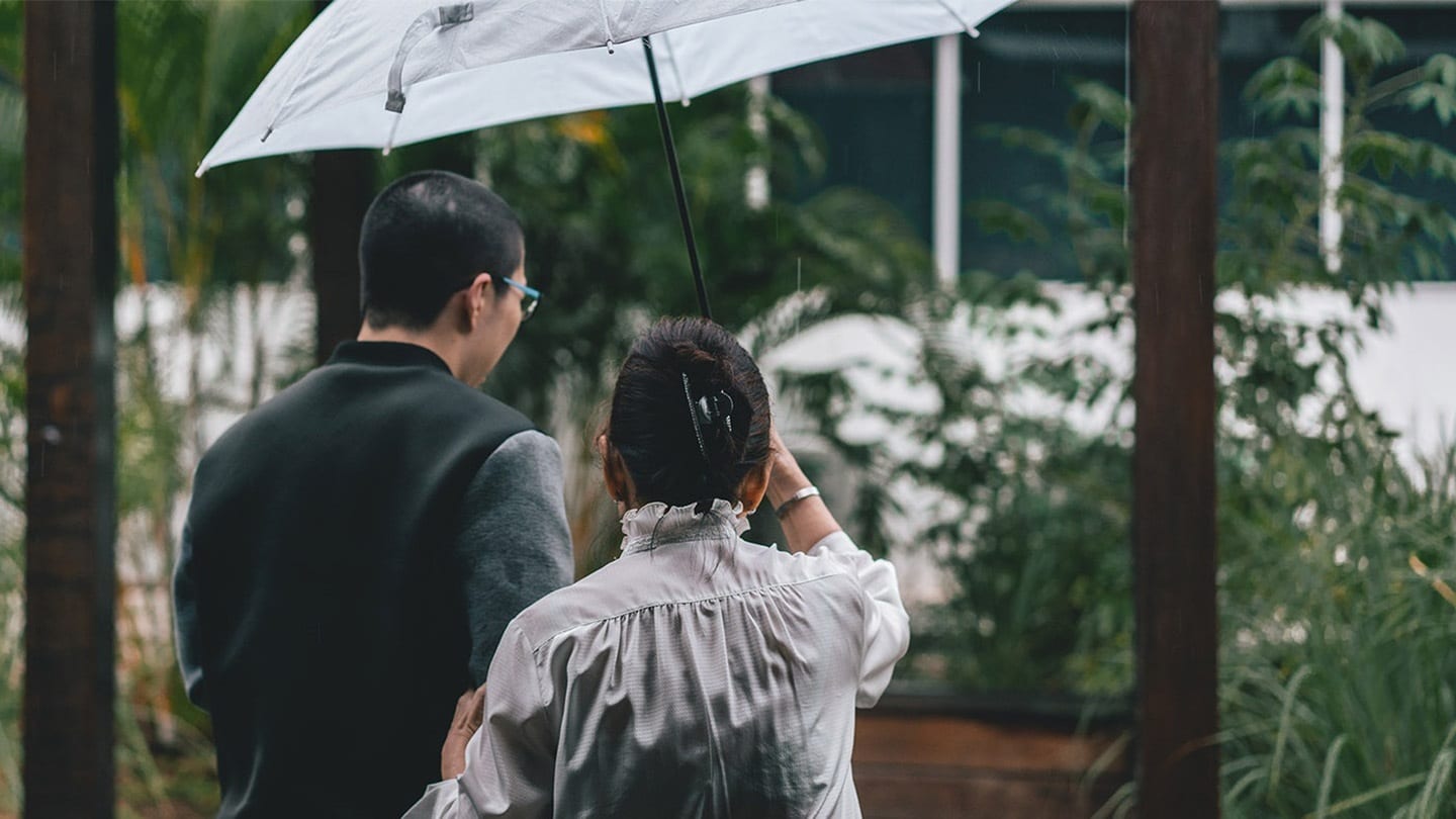 man in black shirt and woman in white blouse sharing a white umbrella