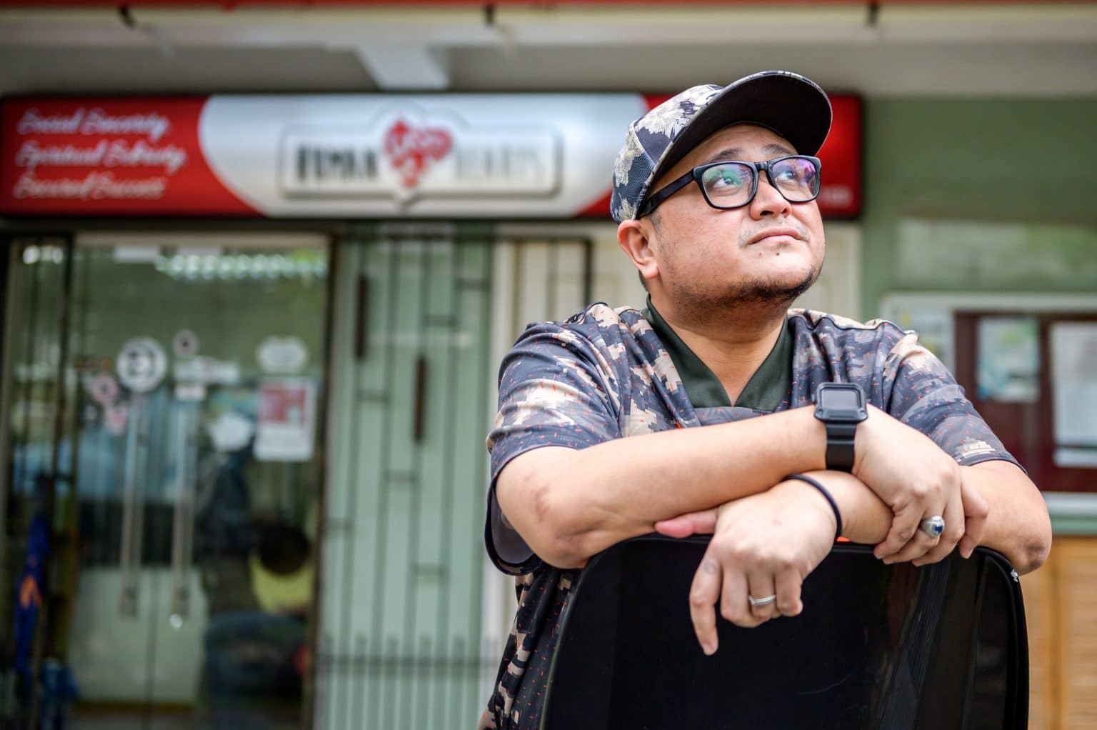 ex-offender in matching cap and shirt staring up wistfully