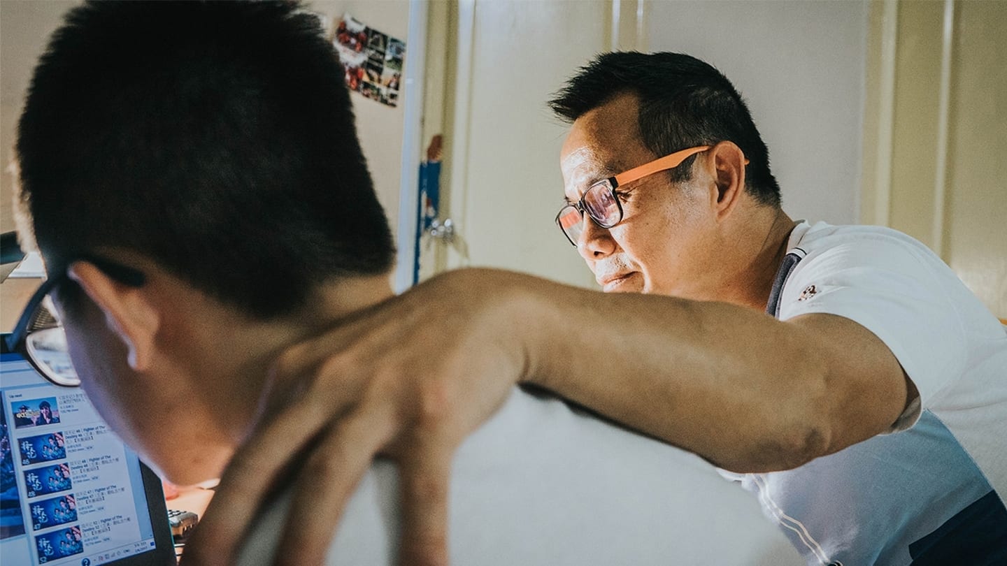 father and son looking at video on laptop