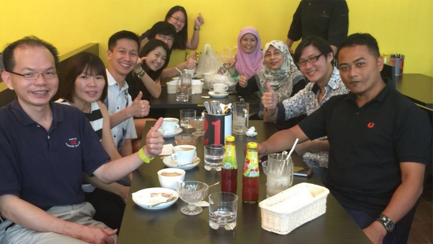 group of people in a restaurant posing in front of a yellow wall