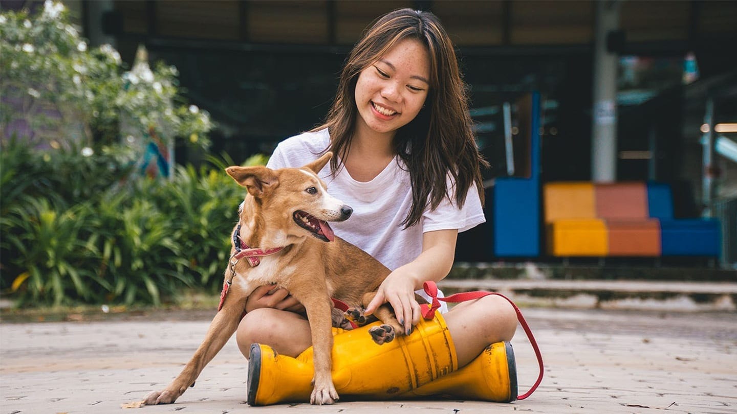 girl in orange boots playing with dog