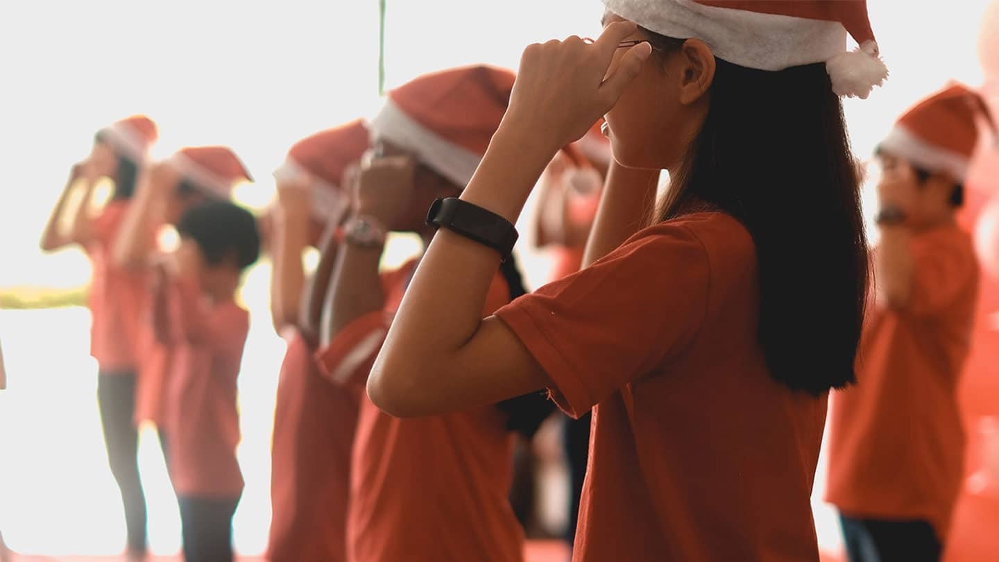 children in christmas hats and red shirts standing in rows