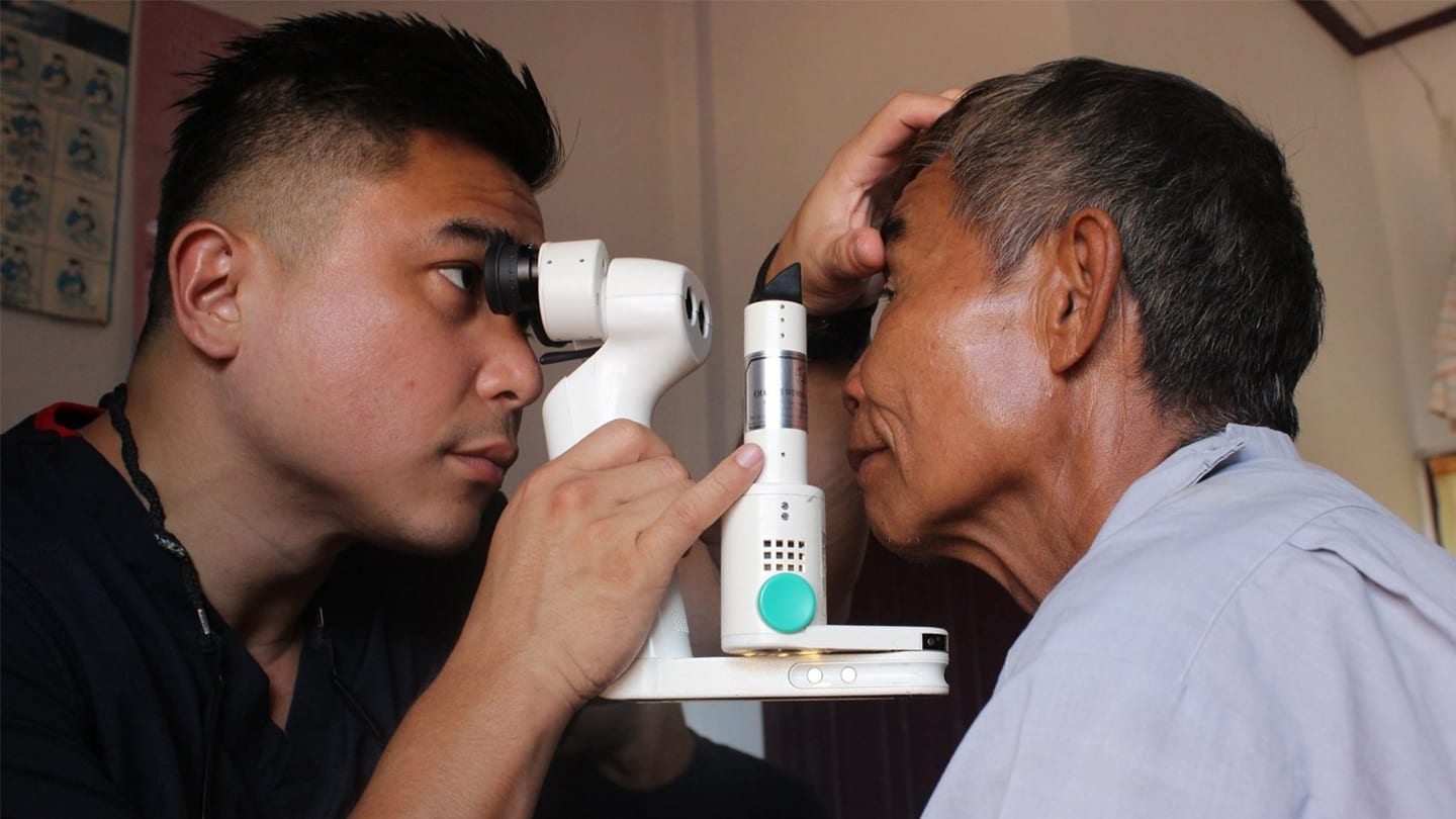 man in black shirt administering eye test on elderly man