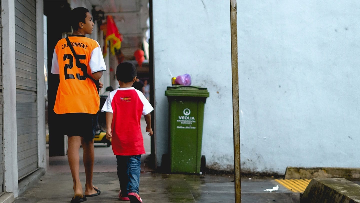 two malay boys walking under a hdb block