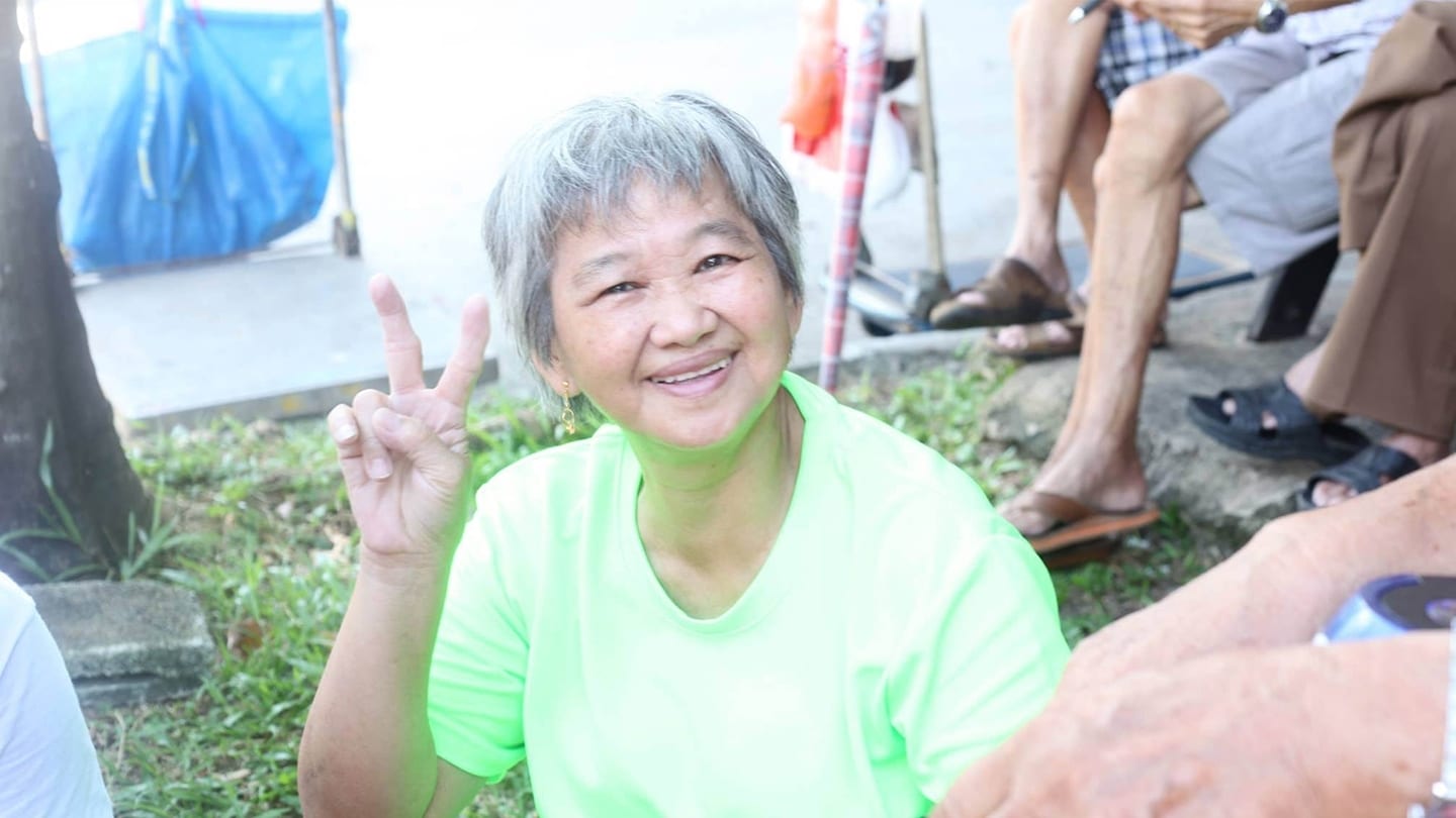 elderly woman in green t-shirt smiles at camera