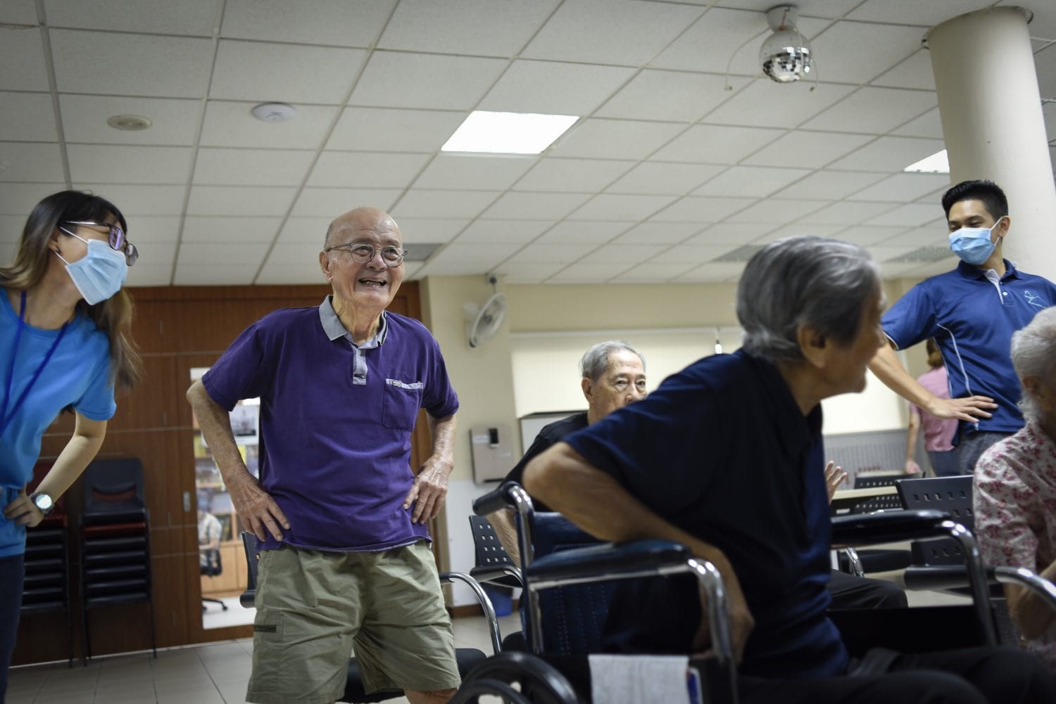 elderly in wheelchair and volunteers all in blue