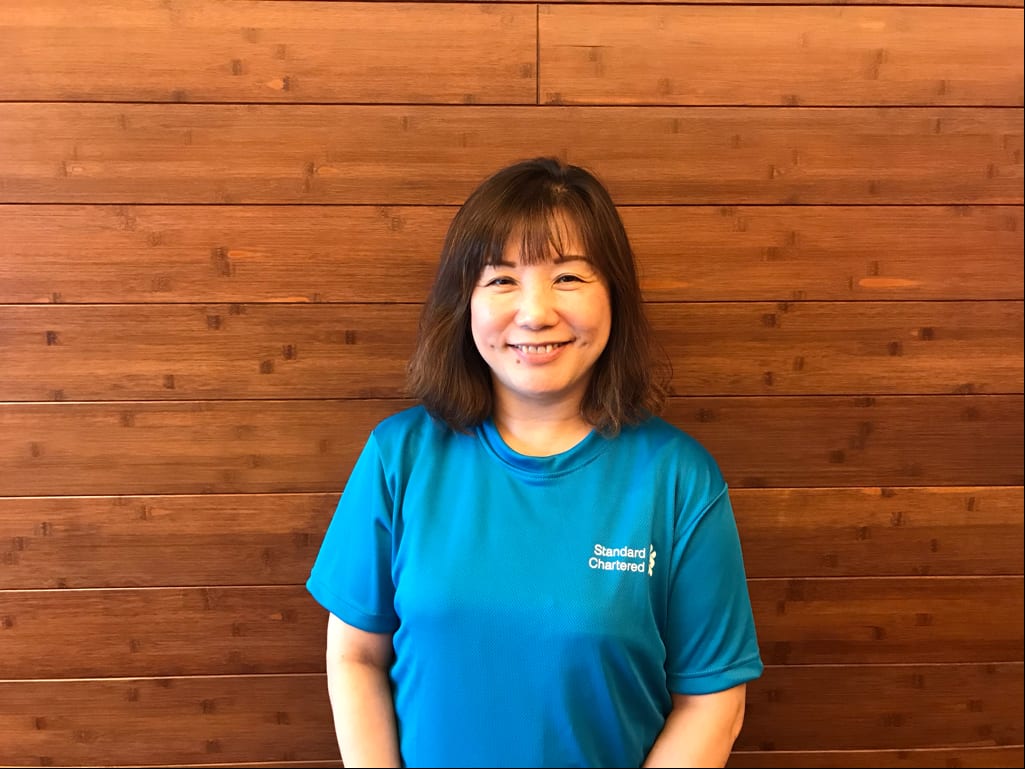 lady in blue shirt with a standard chartered logo