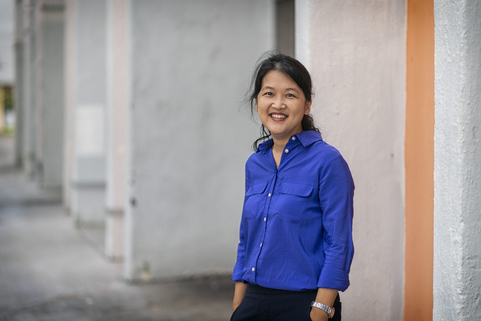 woman in bright blue button up shirt and silver watch smiling at camera