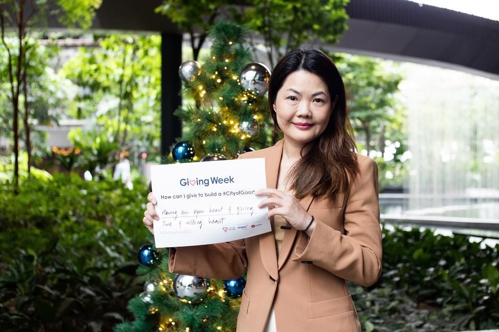 woman in light brown blazer holding up a giving week sign