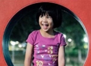 girl in purple shirt standing in a red tunnel