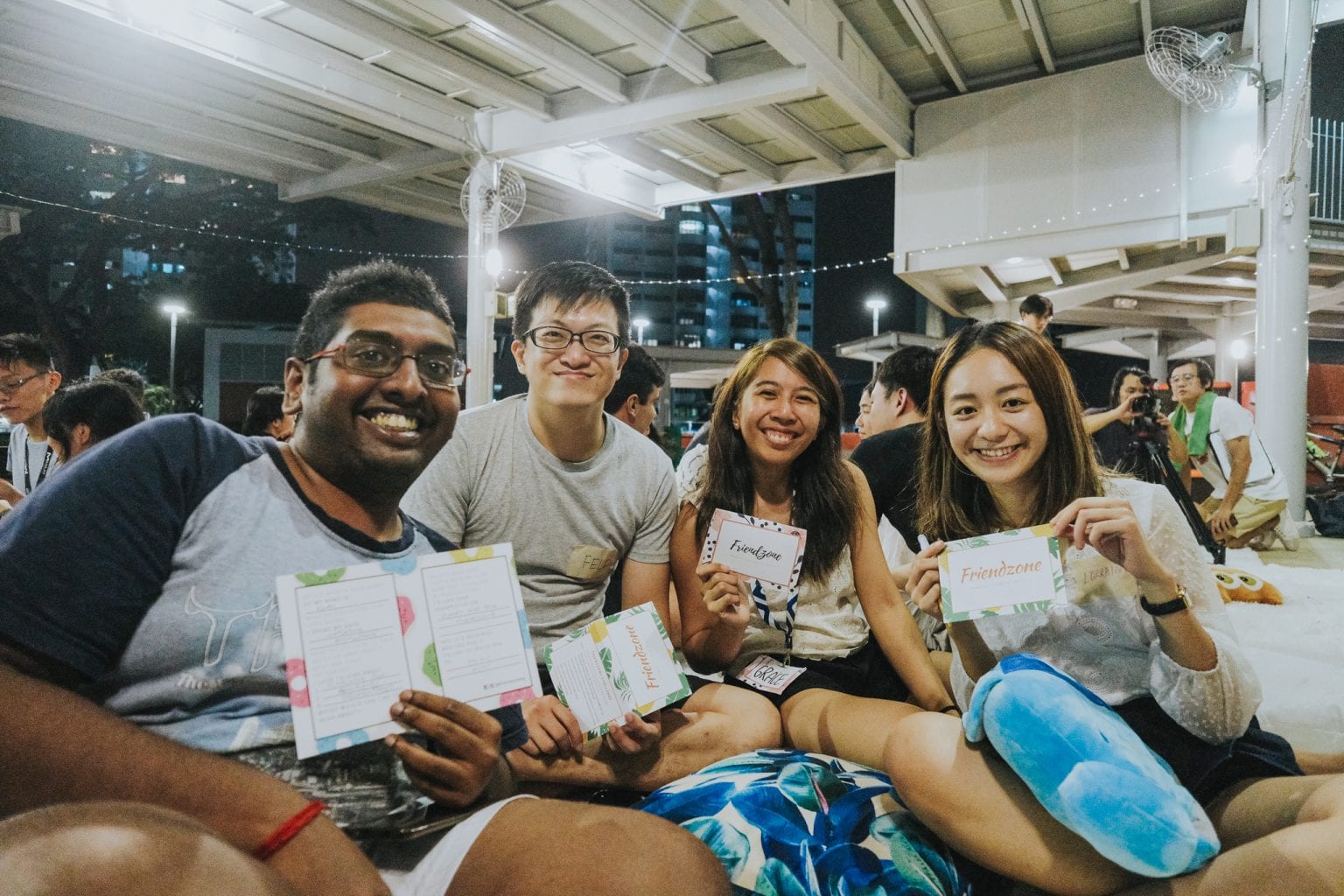 four individuals smiling, holding up cards