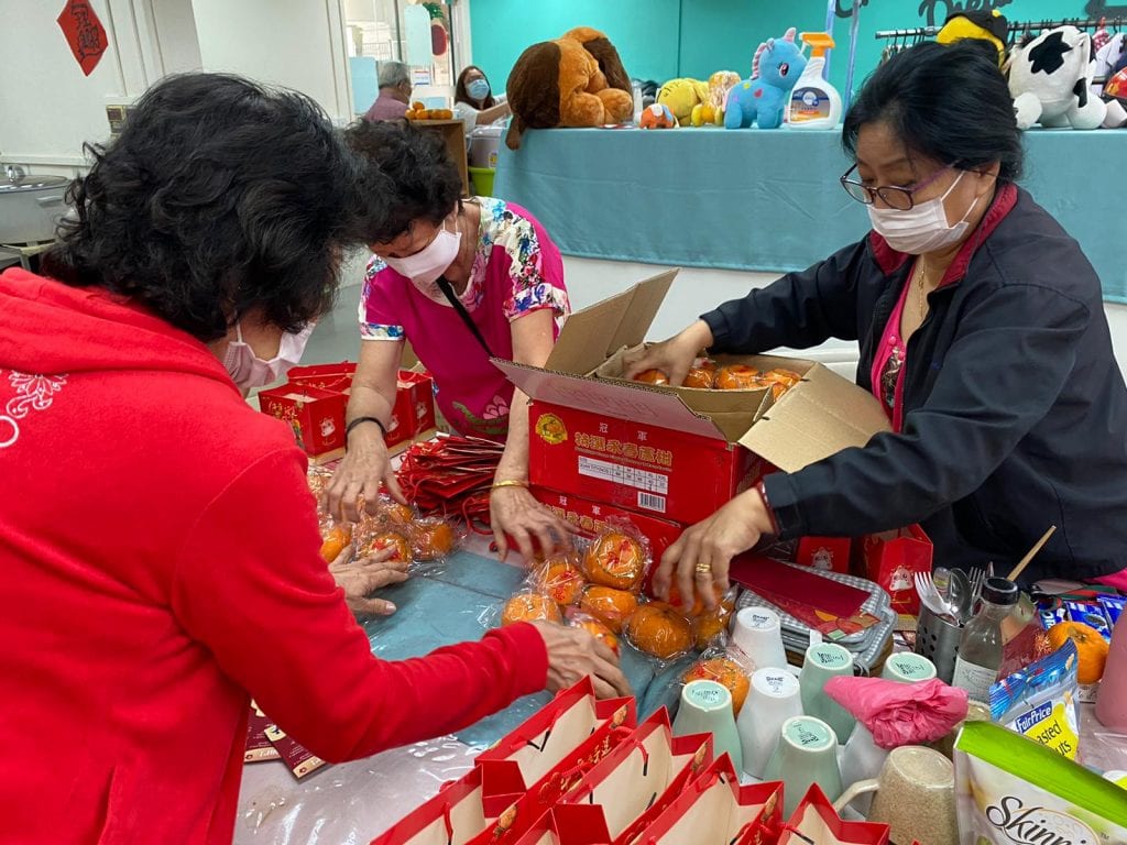 Three women packing mandarin oranges into boxes