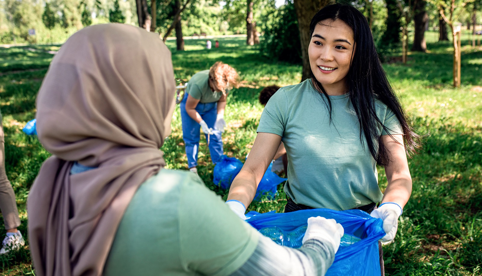 women cleaning up a park with rubbish bags