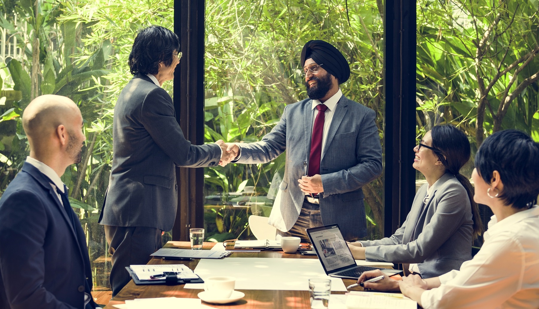 businesspeople shaking hands in a meeting room with greenery