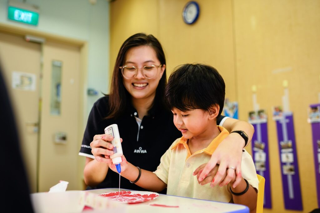 AWWA staff working with a child on a piece of artwork