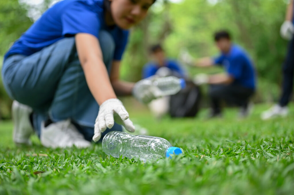 volunteer picking up bottle from grass field