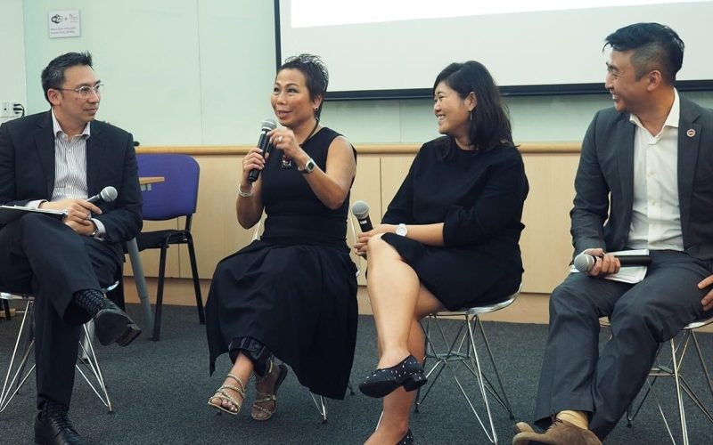 two women and two men all dressed in black giving a talk