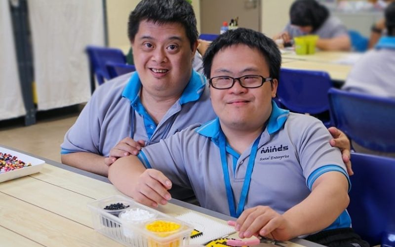 two special needs pupils at MINDS working on a smiley face bead artwork